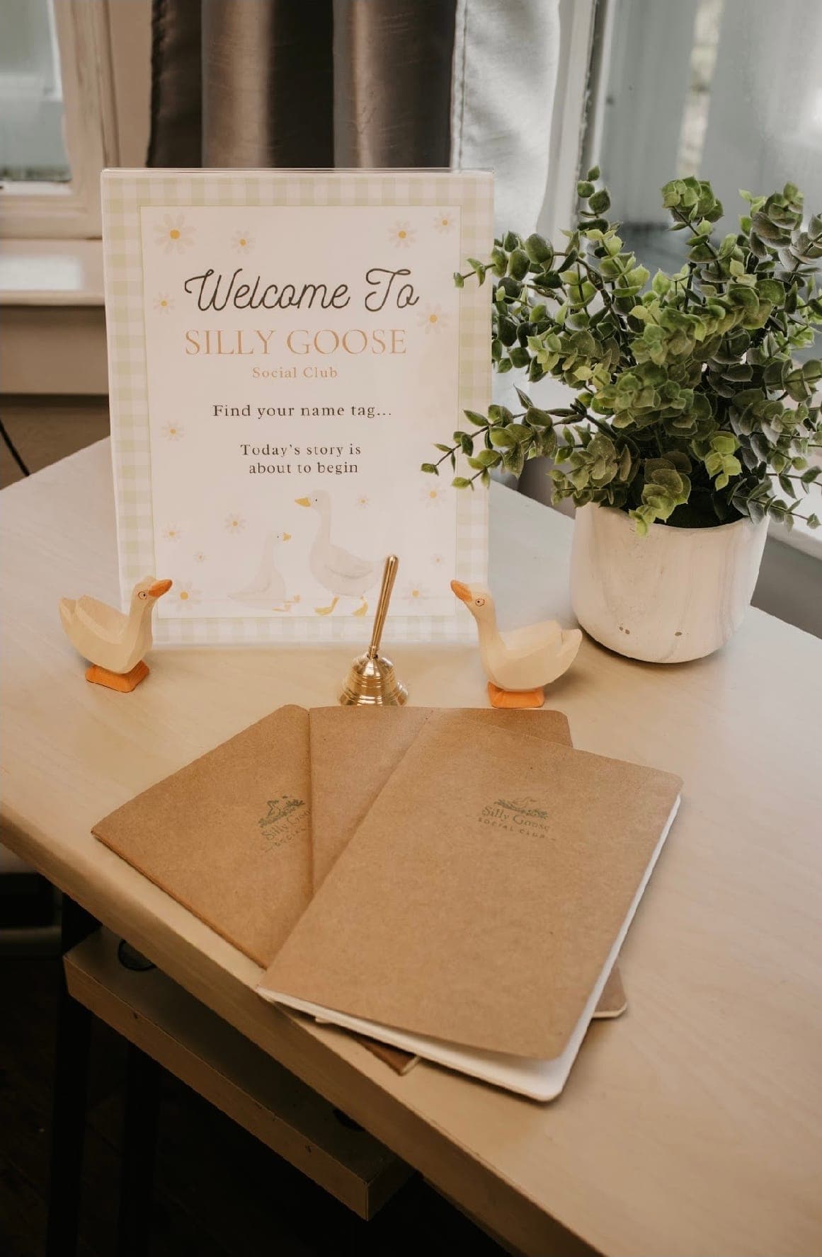 The studio welcome table with the Silly Goose sign, wooden geese, and kraft journals waiting for little hands